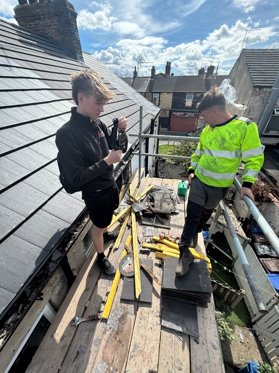 One of us filming on a roof scaffold with a roofer in hi-vis, on a shoot day